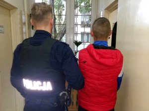Policjant podczas doprowadzenia zatrzymanego mężczyzny do komisariatu Policji