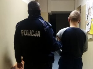 Umundurowany policjant doprowadzający zatrzymanego do jednostki Policji