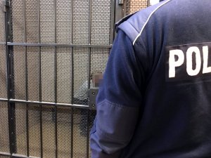 Policjant umundurowany z zatrzymanym mężczyzną siedzącym w policyjnej celi