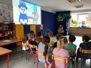 Grupa przedszkolaków w trakcie projekcji filmu animowanego o bezpieczeństwie
