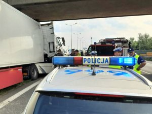 Miejsce zdarzenia drogowego. widoczne radiowozy służb, w tym policji i straży pożarnej z biorącymi udział w czynnościach funkcjonariuszami