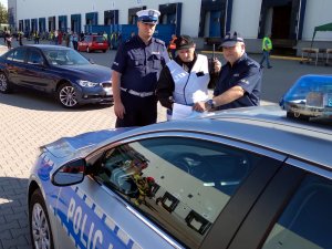 Funkcjonariusze przy radiowozie w tle pojazdów Straży Pożarnej na miejscu awarii przemysłowej