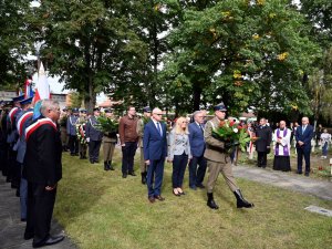 Goście składają wieńce i wiązanki przy pomniku na cmentarzu wojennym