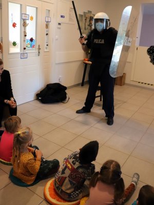 Policjant prezentuje dzieciom wyposażenie do służby
