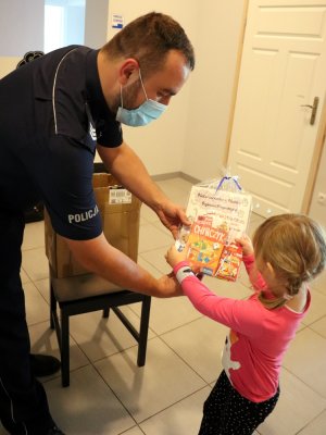 Policjant przekazuje dzieciom upominki ufundowane przez Gminną Komisję Rozwiązywania Problemów Alkoholowych