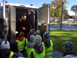 Dzielnicowy prezentuje dzieciom policyjny radiowóz