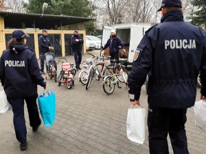 Komendant z przygotowanymi paczkami z akcesoriami rowerowymi, w tym elementy oświetlenia, odblaski i kaski dla dzieci