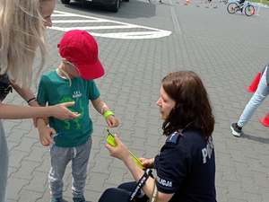 Policjantka zakłada opaskę odblaskową na rękę dziecka
