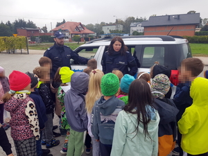 Dzieci podczas spotkania z policjantami na tle oznakowanego radiowozu