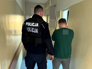 Policjant z zatrzymanym mężczyzną podczas doprowadzenia do komisariatu