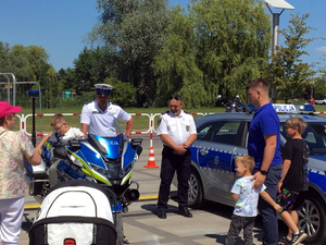 Policjanci podczas pikniku prezentują policyjny motocykl oraz radiowóz