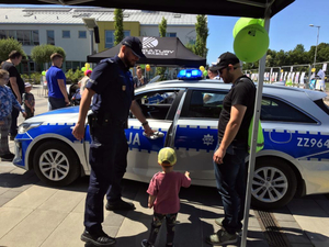 Policjanci podczas pikniku prezentują policyjny motocykl oraz radiowóz