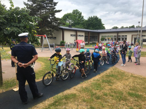 Policjant ruchu drogowego na torze rowerowym razem z przedszkolakami na rowerkach