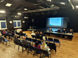 sala widowiskowa w Domu Kultury Łomianki, w której znajdują się uczestnicy debaty społecznej oraz policjanci siedzący za stołem prezydialnym
