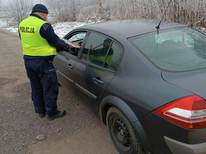 Policjant przekazuje kierowcy zestaw z odblaskowymi gadżetami