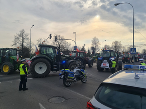 Policjanci zabezpieczają przejazd  kolumny maszyn rolniczych po drodze krajowej 92