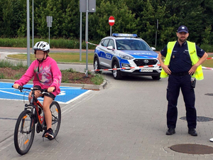 Policjant podczas przejazdu rowerem uczennicy zdającej egzamin na kartę rowerową