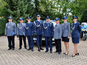 Zdjęcie grupowe policjantów na tle oznakowanych radiowozów