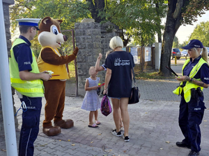 Policjanci wspólnie z maskotką Wiewiórką Sonią rozdają dzieciom elementy odblaskowe