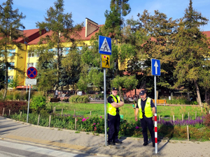 Funkcjonariusze Straży Gminnej na tle szkoły podstawowej