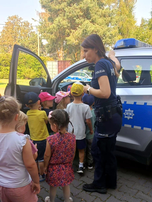 Policjantka prezentuje przedszkolakom oznakowany radiowóz