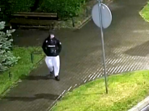 wizerunek jednej osoby w czarnej kurtce z kapturem, z jasnym paskiem na klatce piersiowej, jasnych spodniach i czarnych butach