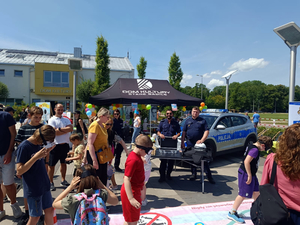 Policjanci na stoisku promocyjnym Policji podczas pikniku razem z jego uczestnikami