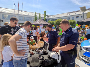 Policjanci na stoisku promocyjnym Policji podczas pikniku razem z jego uczestnikami