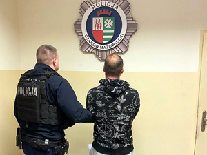 Umundurowany policjant doprowadza zatrzymanego mężczyznę