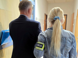 Policjantka doprowadza zatrzymanego mężczyznę na czynności do komendy