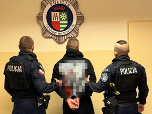 Umundurowani policjanci doprowadzają zatrzymanego mężczyznę do komisariatu