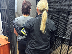 Policjantka doprowadza zatrzymaną kobietę do pomieszczenia dla osób zatrzymanych