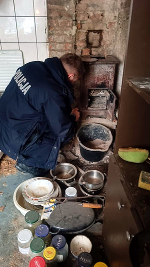 Dzielnicowy pomaga mieszkańcowi napalić w piecu
