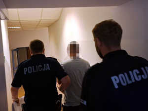 Policjanci doprowadzają zatrzymanego mężczyznę do zakładu karnego
